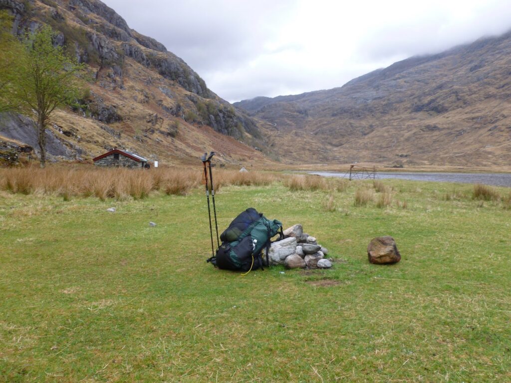 Rucksack packed and leaning on pile of stones left over from an old camp fire