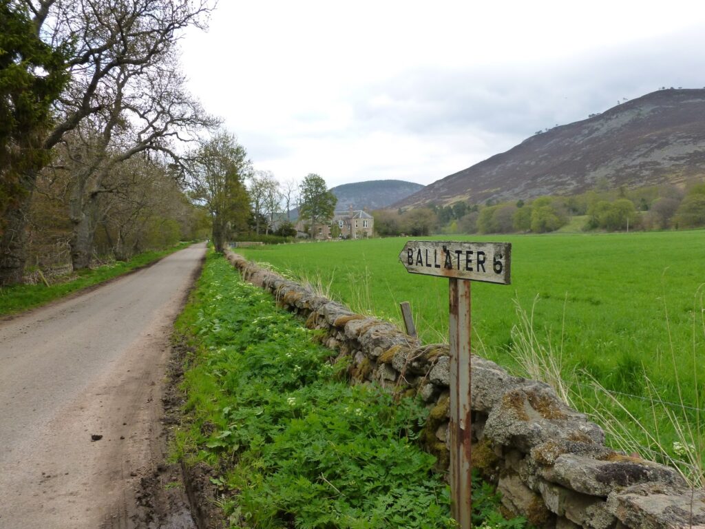 Weathered sign saying, "Ballater 6 miles"