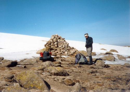 Mike at the cairn top of Braeriach with snowfield in background.