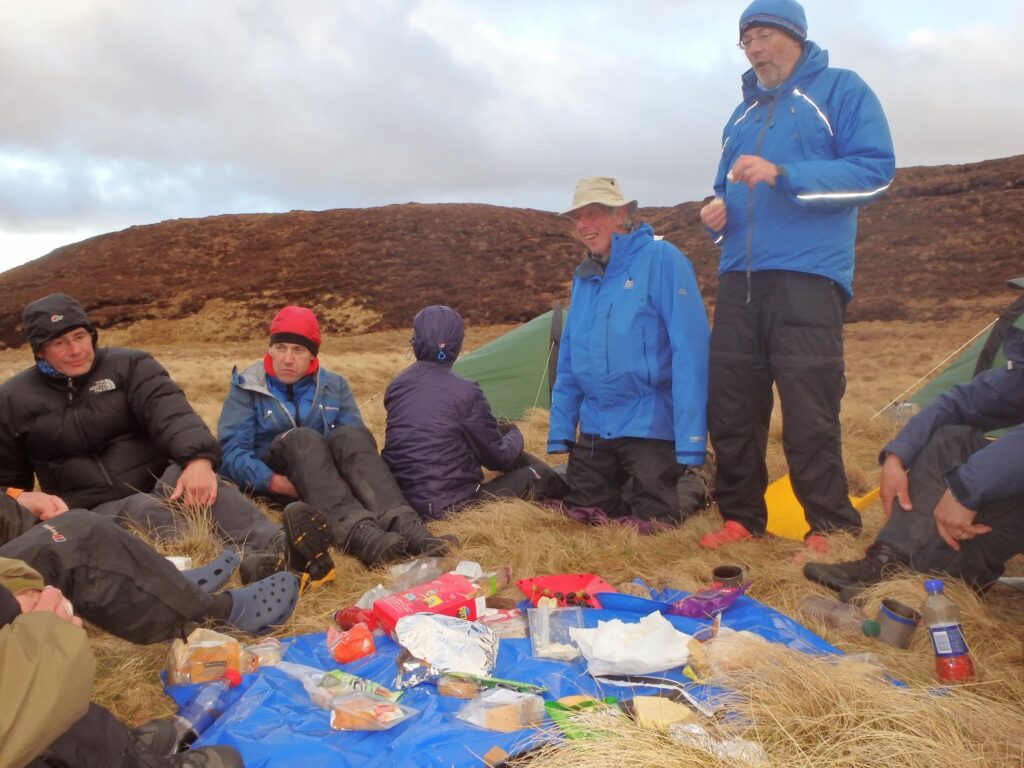 tarp spread with cheese & wine etc. Partygoers around it.