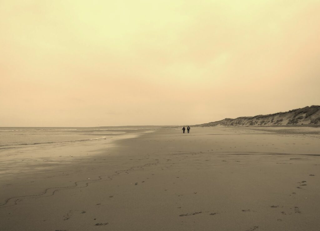 two figures in distance leaving a now deserted beach