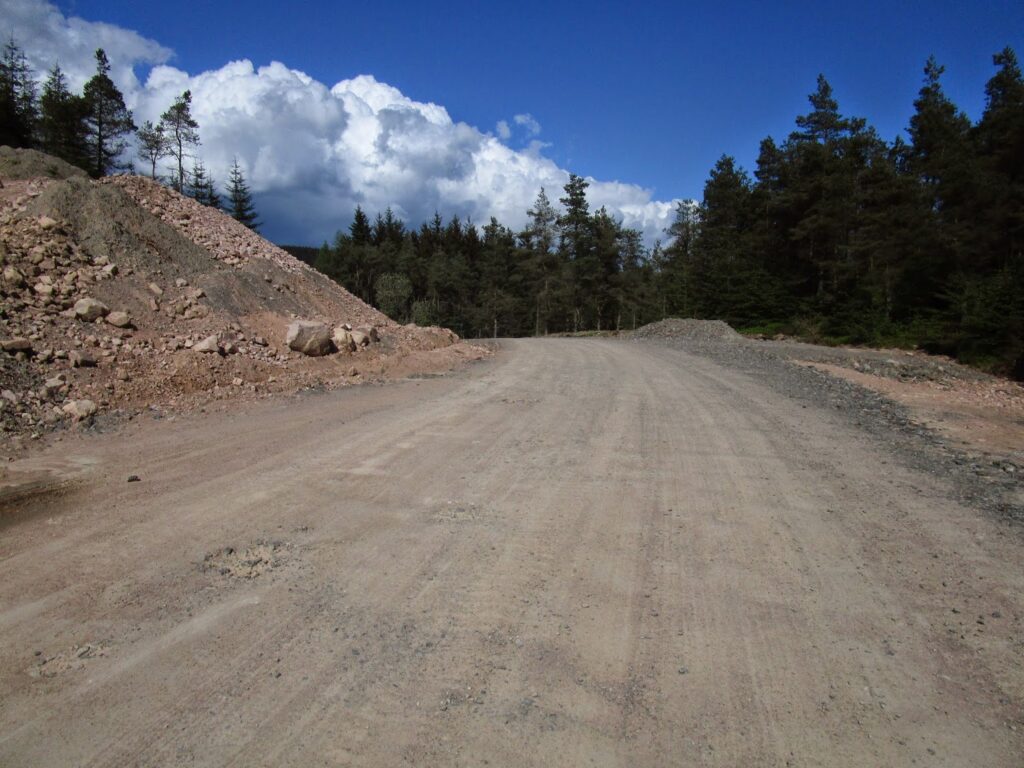 Wide bulldozed construction highway through the forest
